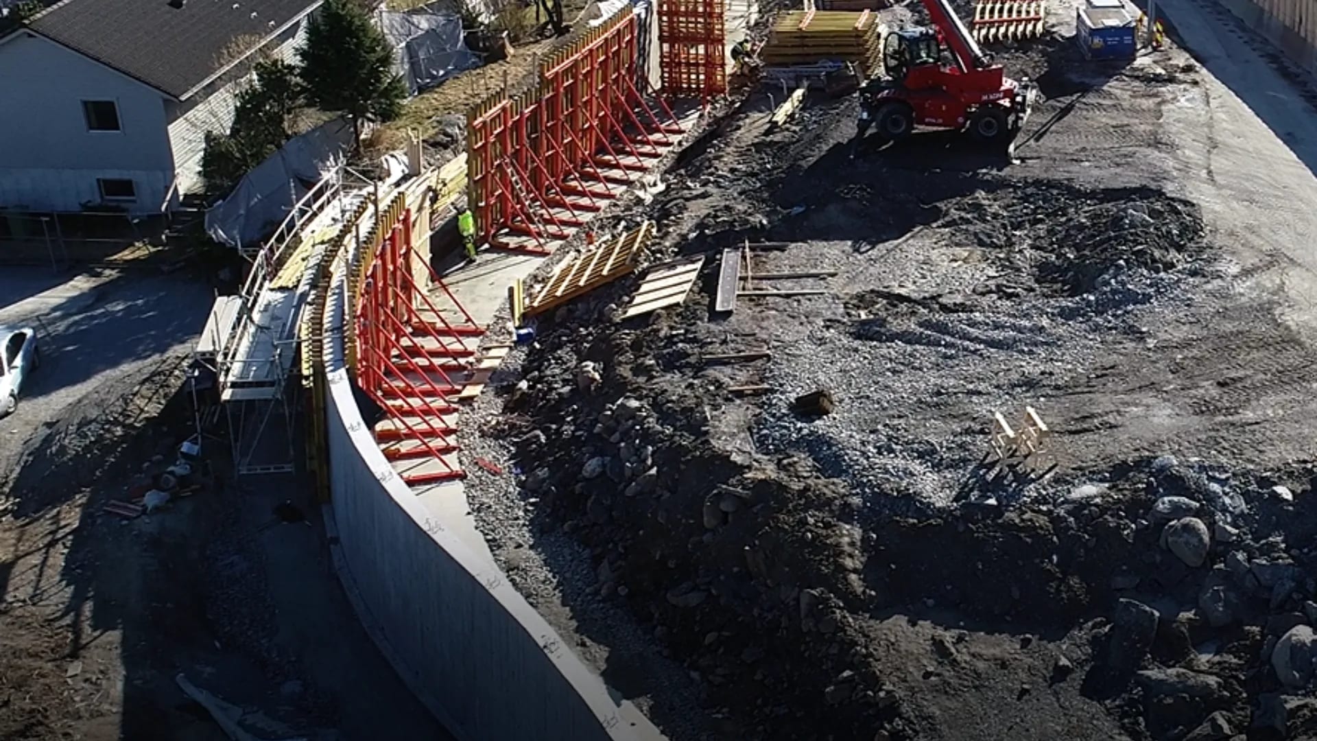 Concrete retaining wall with red system formwork alongside a road alignment.