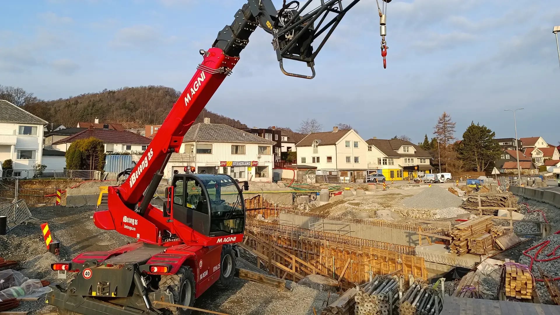 The telehandler reaching over the excavation where the retaining walls take shape.