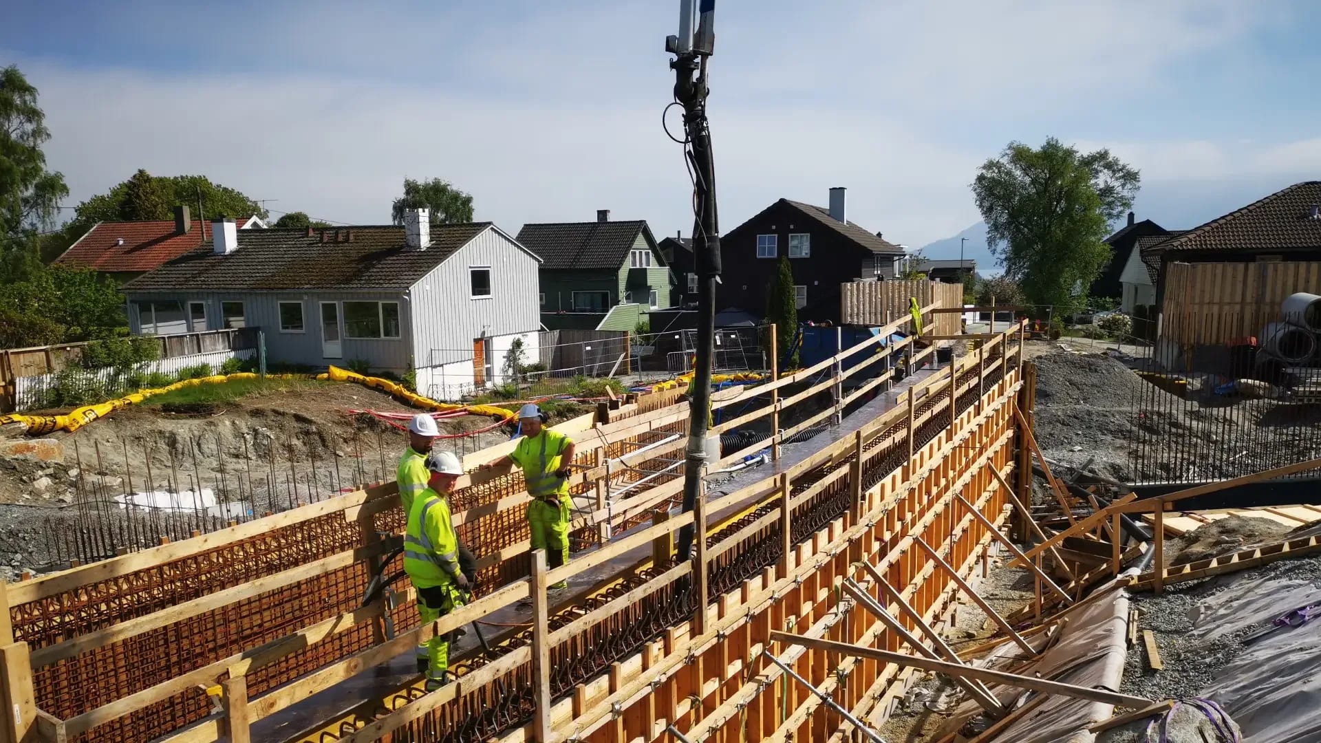 The crew pouring a wall with the pump hose down in the formwork, close to the houses along the route.