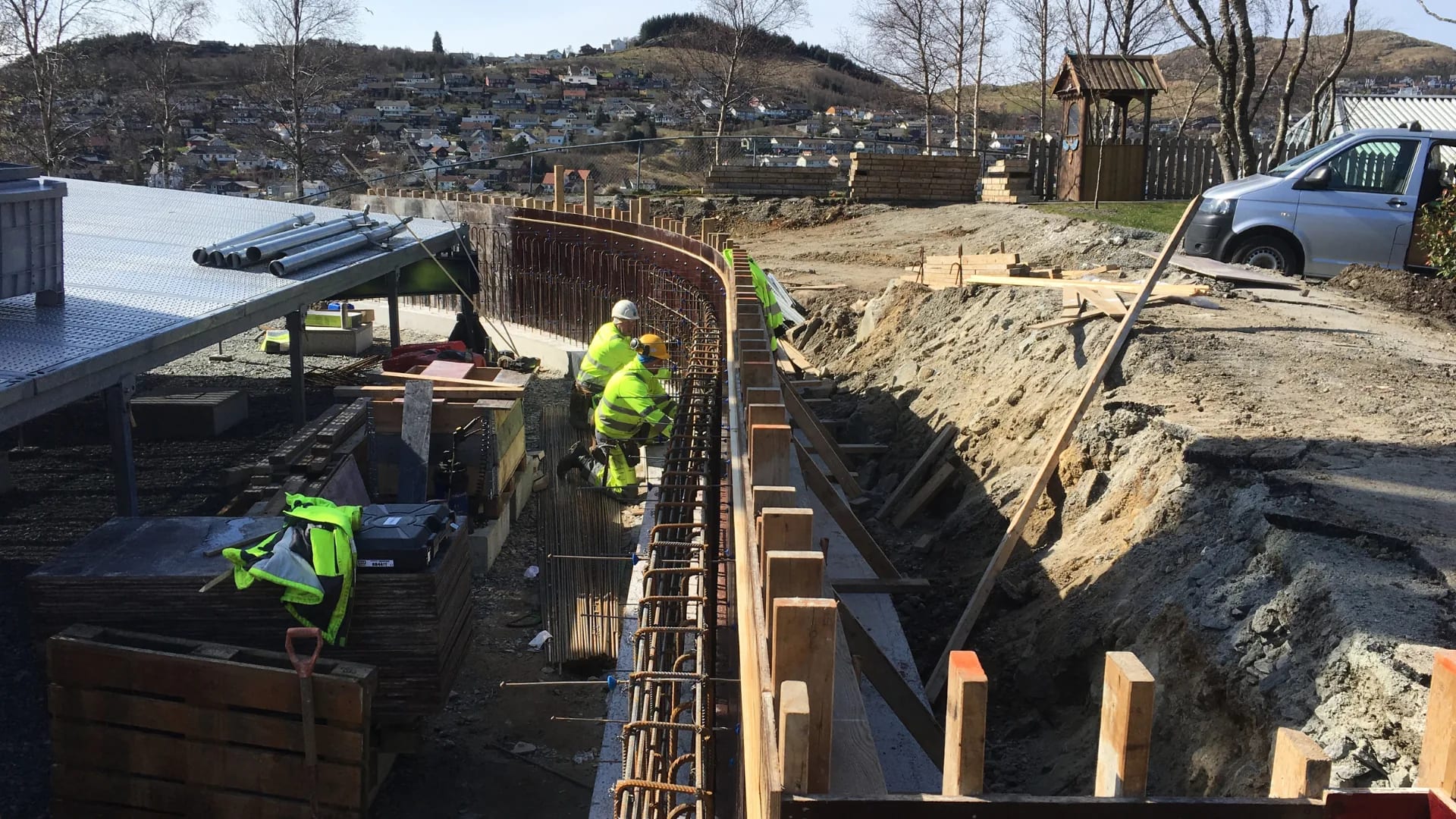 Concrete workers tying reinforcement in an excavated trench.